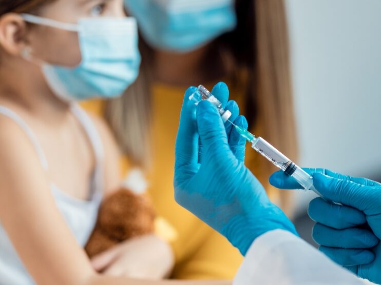 doctor filling the syringe while the child is sitting in the background